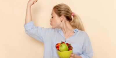 frontal joven mujer camisa sosteniendo plato frutas flexionando pared crema fruta modelo mujer pose