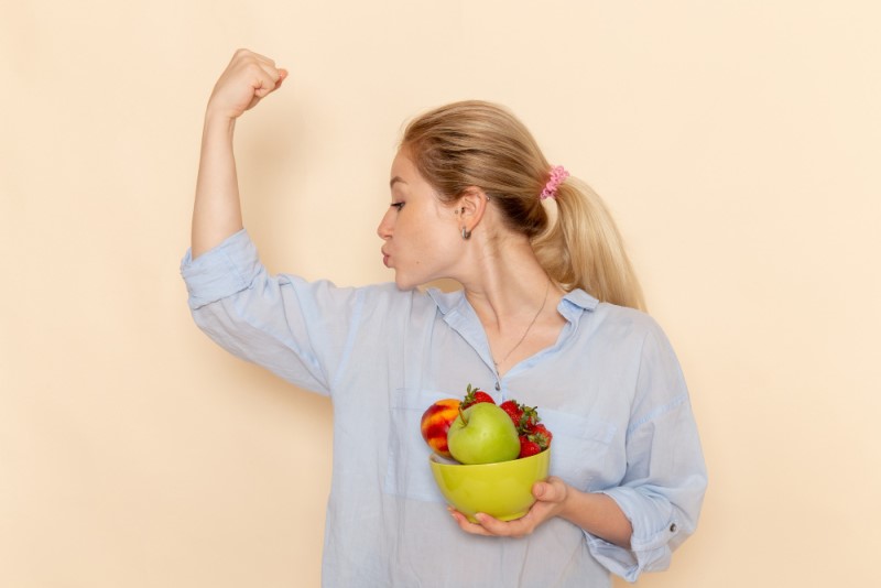 frontal joven mujer camisa sosteniendo plato frutas flexionando pared crema fruta modelo mujer pose