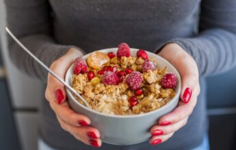 manos mujer sosteniendo bol cereales fruta