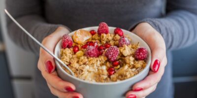 manos mujer sosteniendo bol cereales fruta