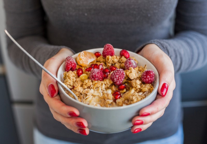 manos mujer sosteniendo bol cereales fruta