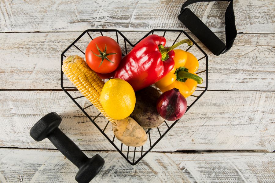 productos saludables en cesta negra con pesas de gimnasio