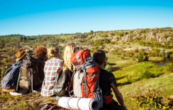 Jóvenes amigos viajeros sentados en roca en el cañón, disfrutando de la vista