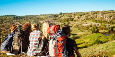 Jóvenes amigos viajeros sentados en roca en el cañón, disfrutando de la vista