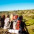 Jóvenes amigos viajeros sentados en roca en el cañón, disfrutando de la vista