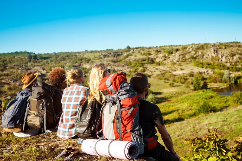 Jóvenes amigos viajeros sentados en roca en el cañón, disfrutando de la vista