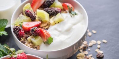 Tazón de granola de avena con yogur, mora fresca, fresas, kiwi menta y nueces