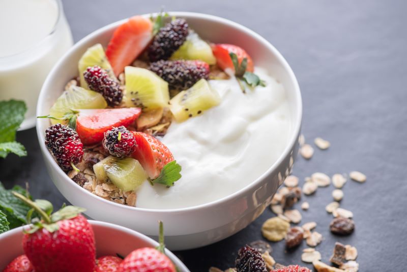 Tazón de granola de avena con yogur, mora fresca, fresas, kiwi menta y nueces