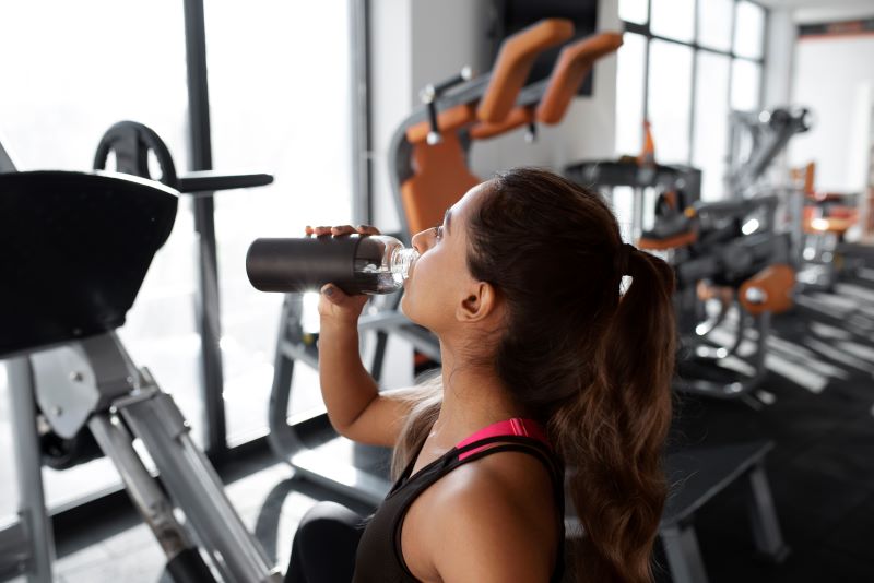 mujer bebiendo en el gimnasio