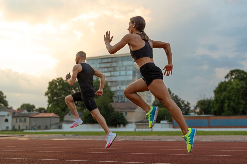 Hombre y mujer corriendo en la pista de atletismo