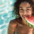 mujer comiendo sandia en la piscina