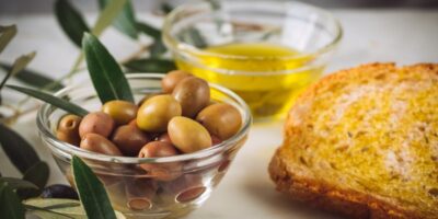 rebanadas de pan con aceite virgen extra cerca de tazones de vidrio llenos de aceite y aceitunas