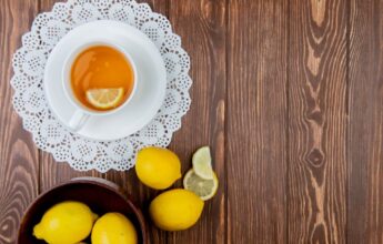 Te de limón sobre mesa de madera junto a limones