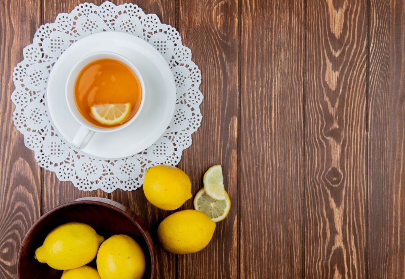 Te de limón sobre mesa de madera junto a limones