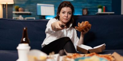 mujer cambiando de canal mientras come comida basura